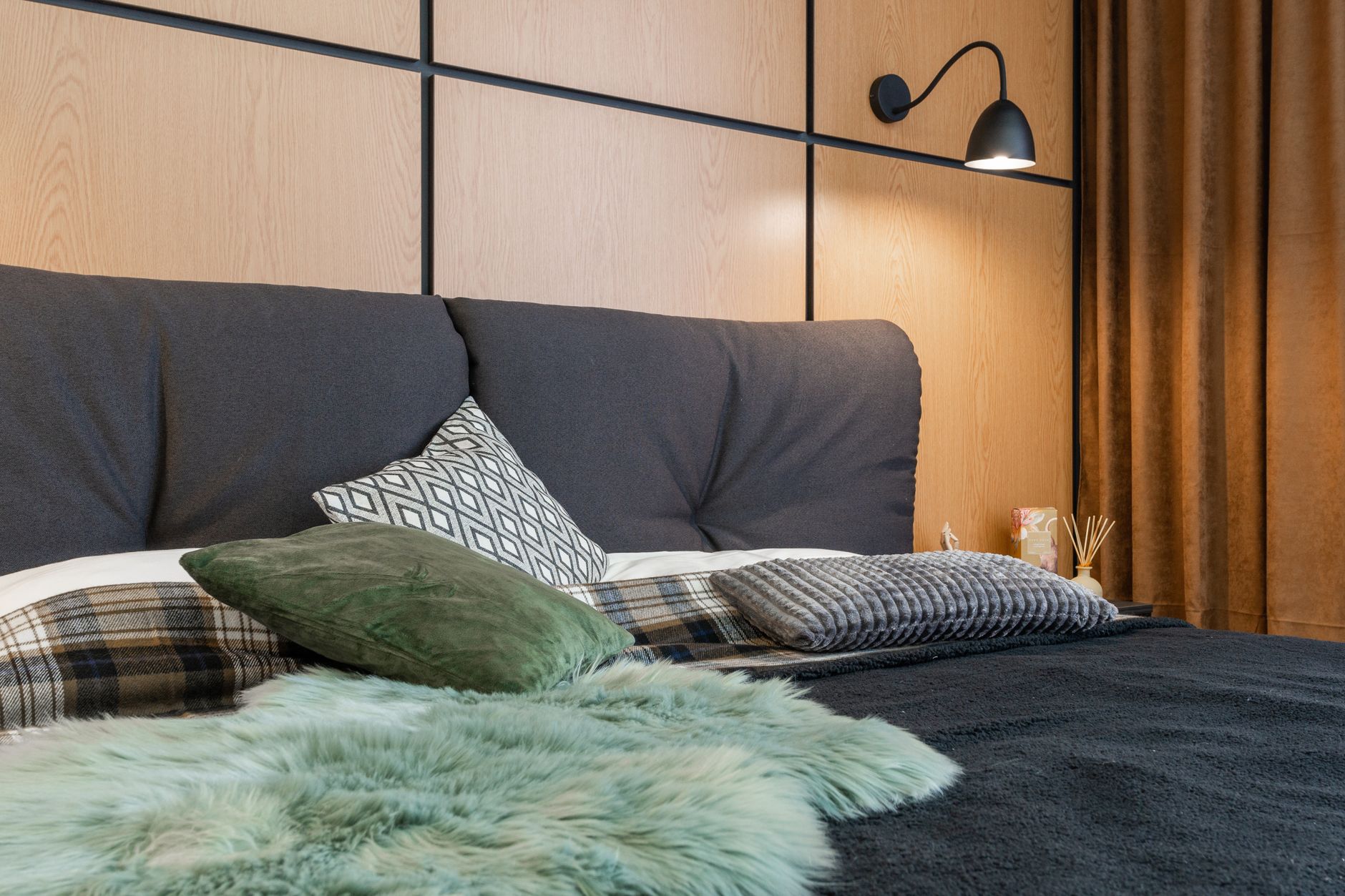 Interior of bedroom with cushions placed on soft bed under lamp hanging above bedside with aroma sticks, illustrating Sloped Ceiling Bedroom: A Feng Shui Guide to the Layout