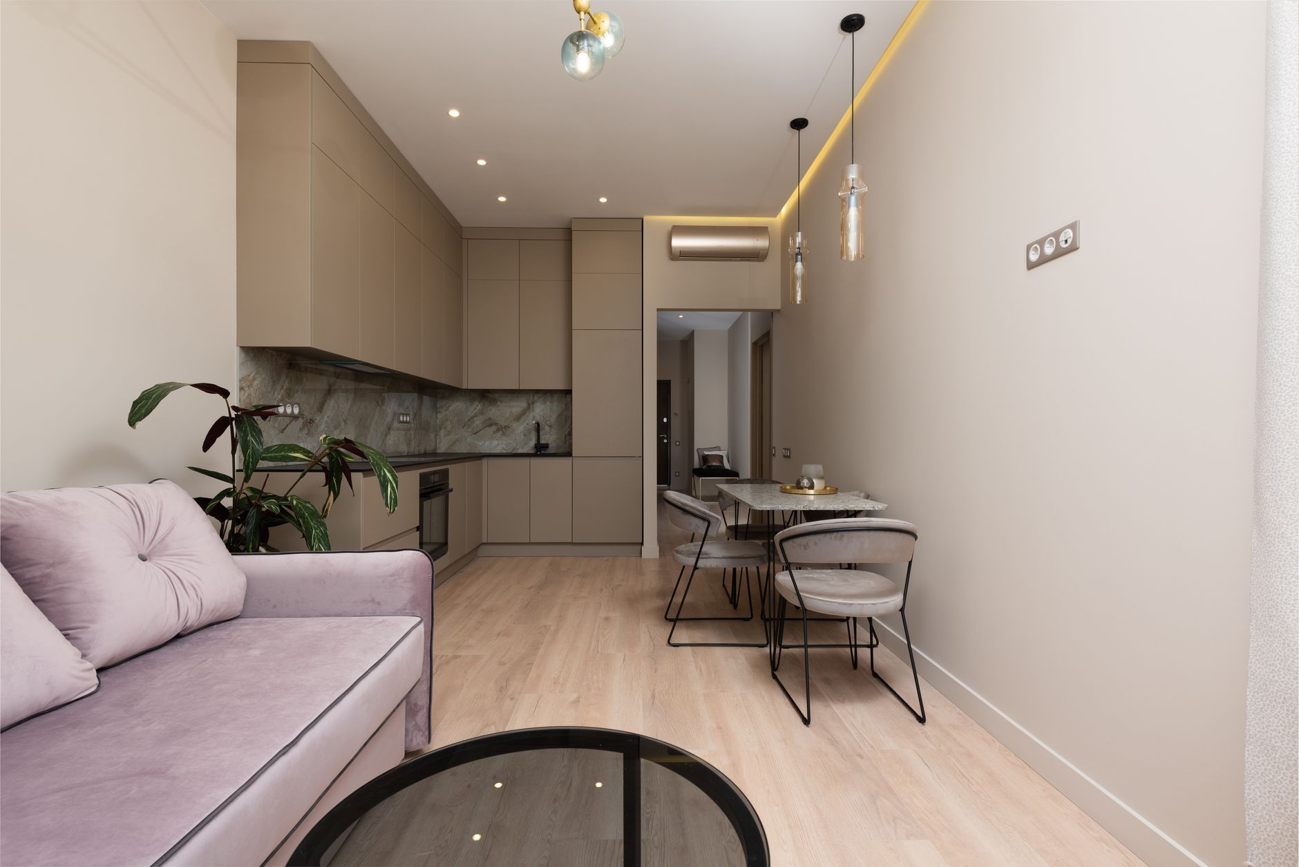 Interior of contemporary home with sofa with pillows next to open kitchen with cupboards near table with chairs near potted plant, illustrating What Does Feng Shui Say About Storag