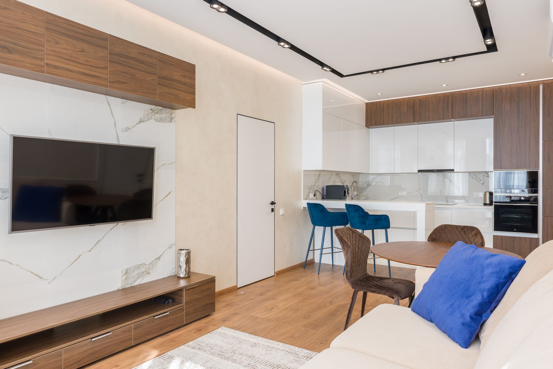 Interior of living room and open kitchen with comfortable sofa TV and chairs placed near round table in modern apartment, illustrating What Does Feng Shui Say About Storage in a Sm
