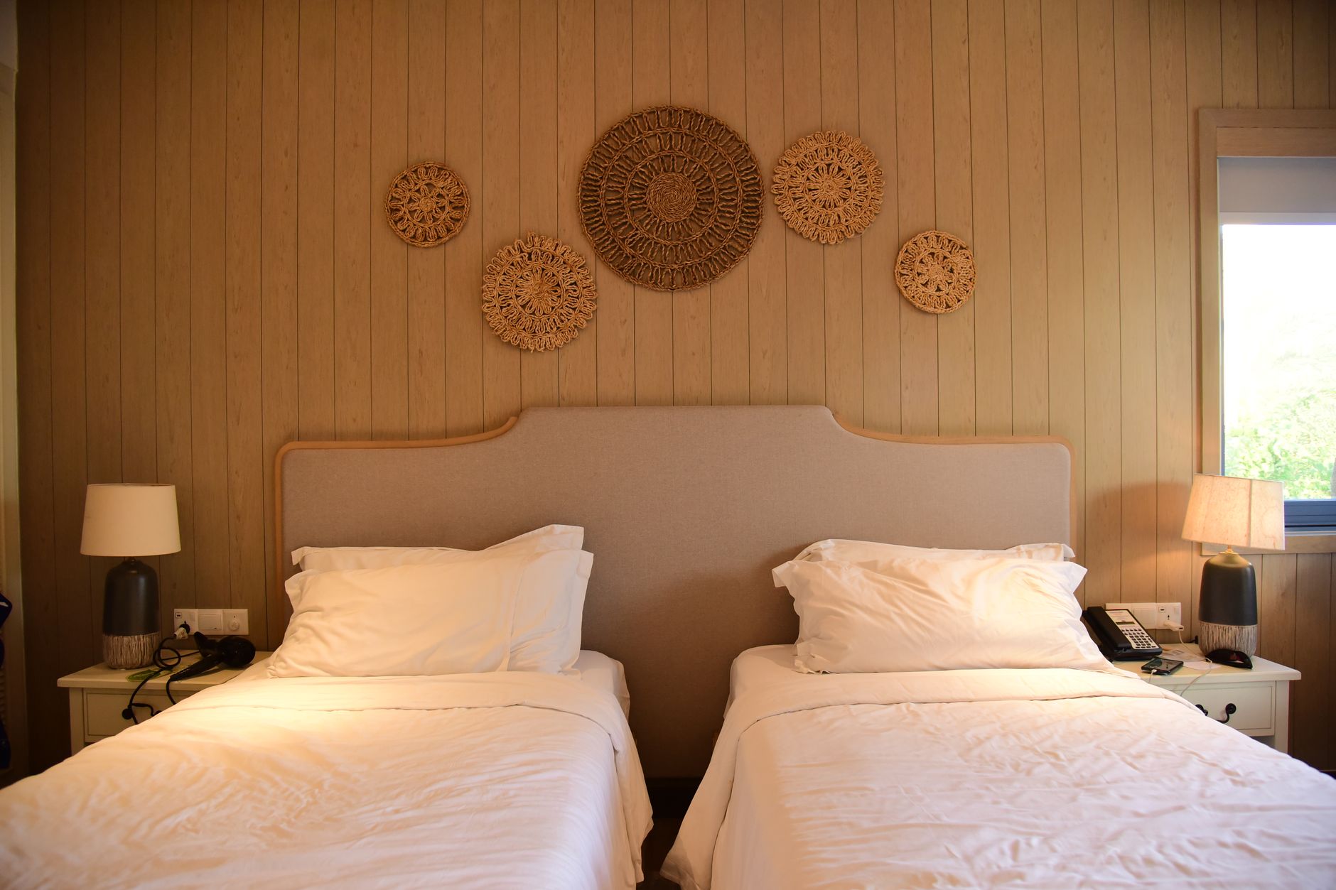 Inviting hotel room with twin beds and artistic wooden wall decor, illustrating What Feng Shui Says About Storing Things Under the Bed