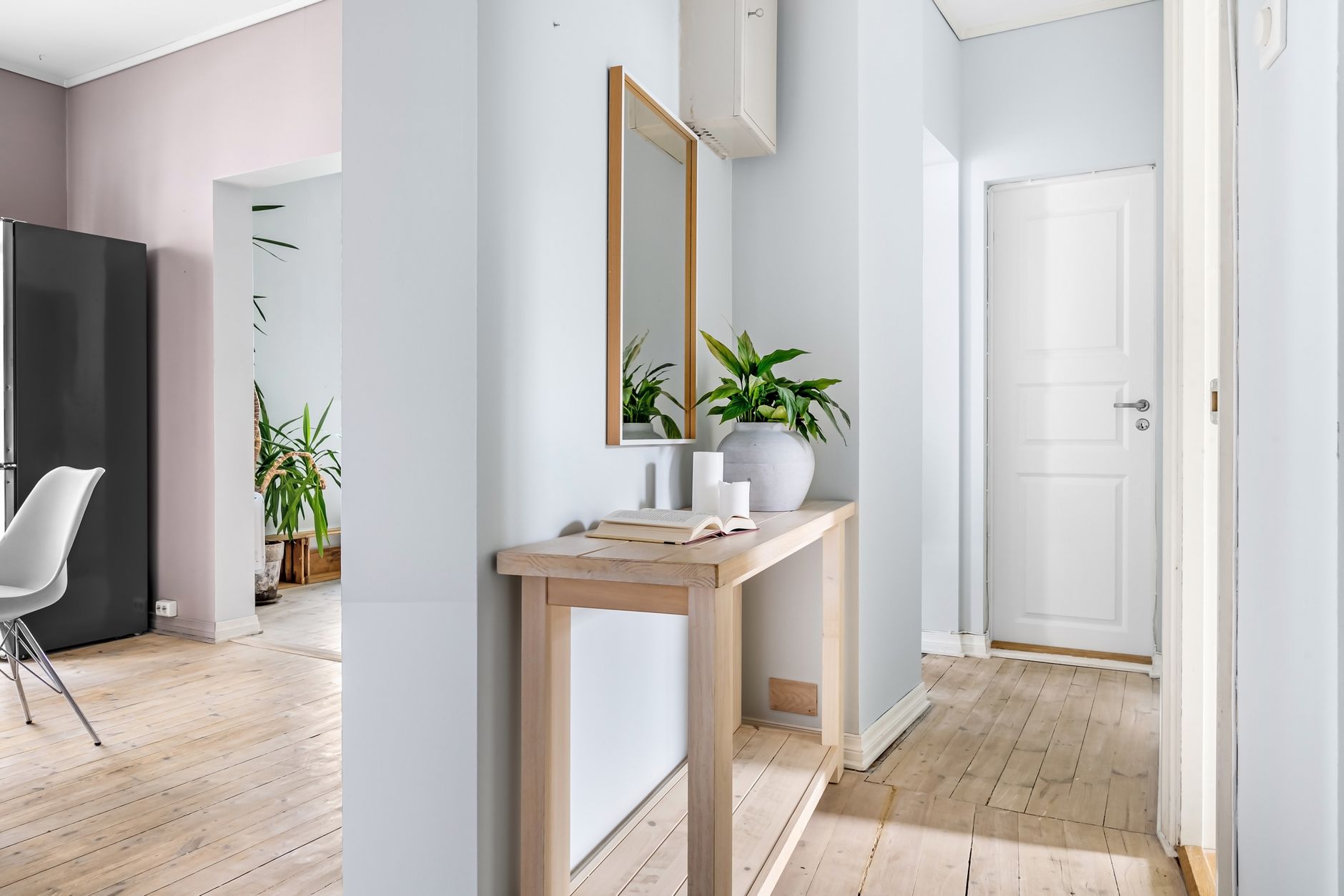 Bright hallway interior featuring minimalist decor, a mirror, and lush plants for a serene ambiance, illustrating Two Doors Facing Each Other: What Feng Shui Actually Says