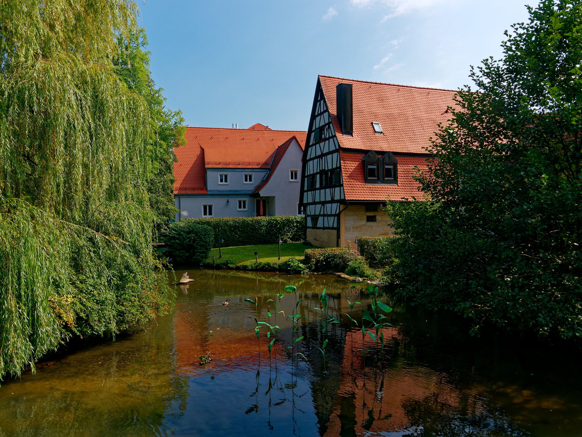Idyllic scene of traditional timber-framed homes beside a serene pond in Hersbruck, Germany