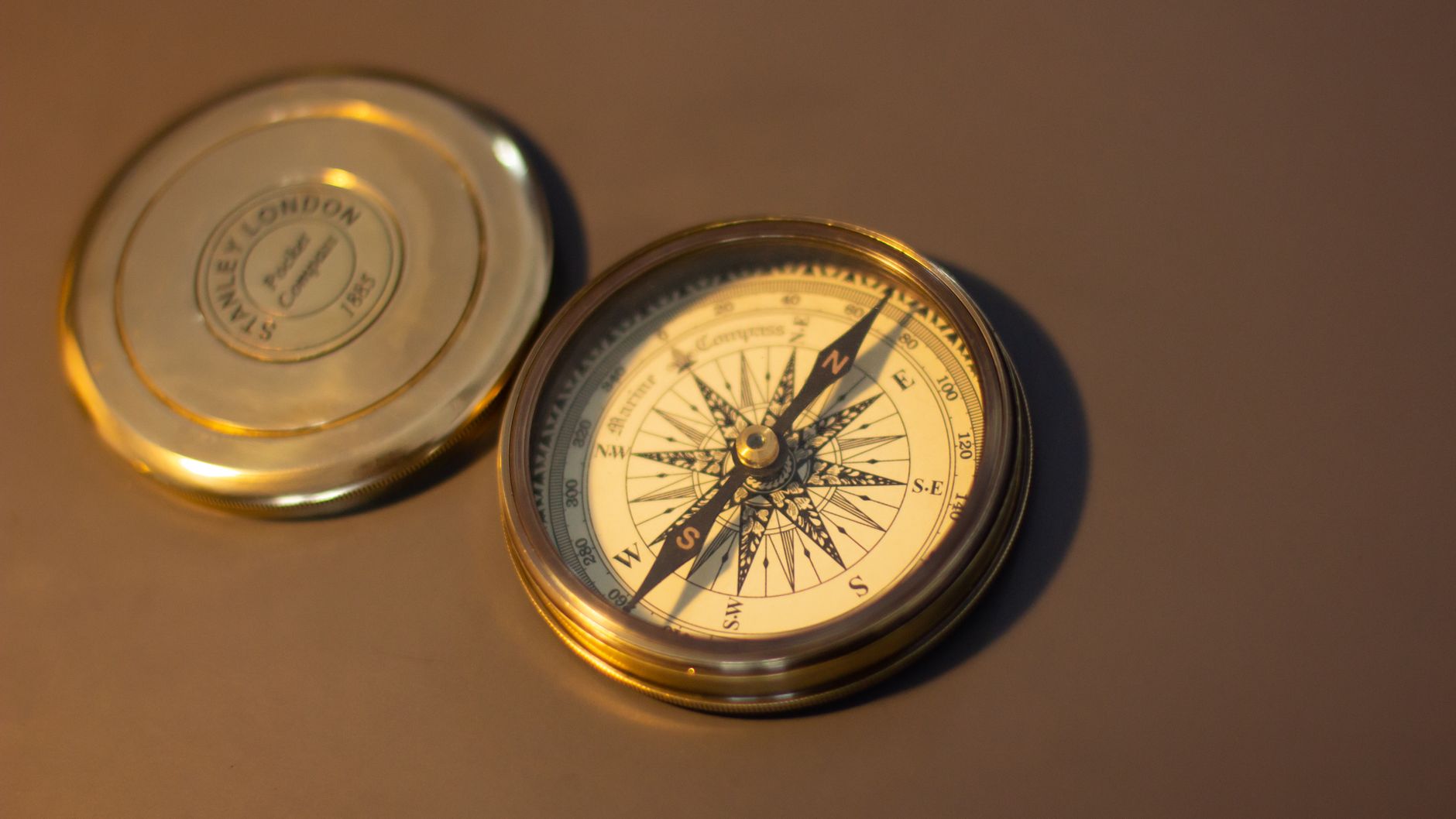 A close up of a vintage brass compass on a warm brown surface, perfect for exploration themes, illustrating What Is a Feng Shui Compass, and Do You Need One