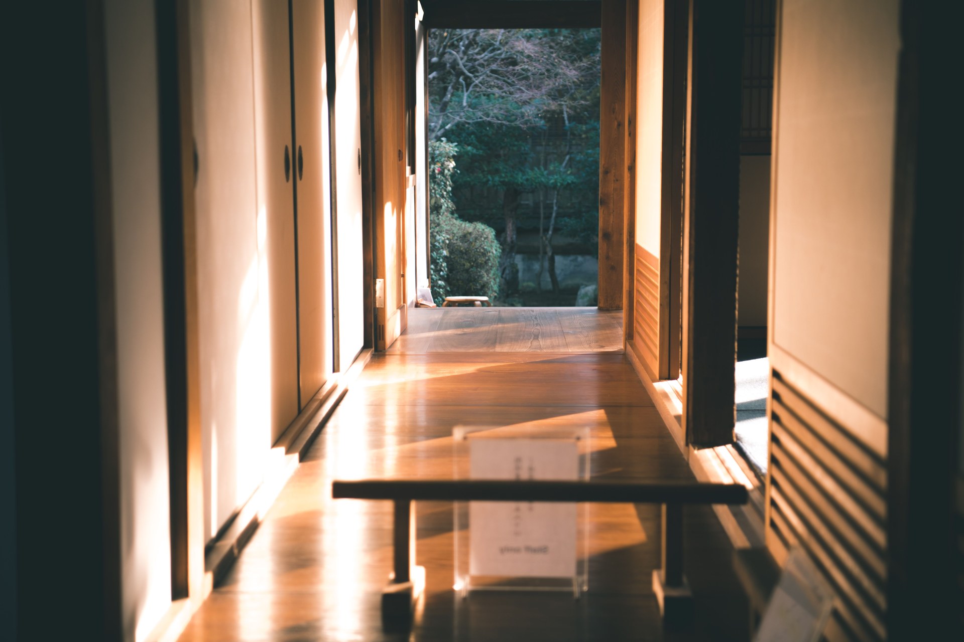 A tranquil Japanese interior hallway with wooden floors and sliding doors illuminated by sunlight
