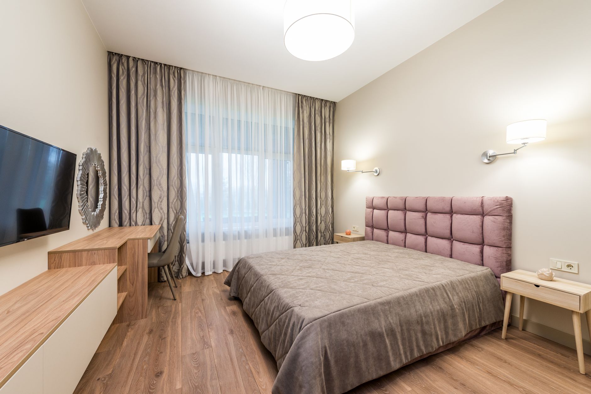 Contemporary bedroom with TV and curtains decorating window under bright luminous round shaped lamps, illustrating Where Should the Bed Go in a Bedroom? A Feng Shui Guide