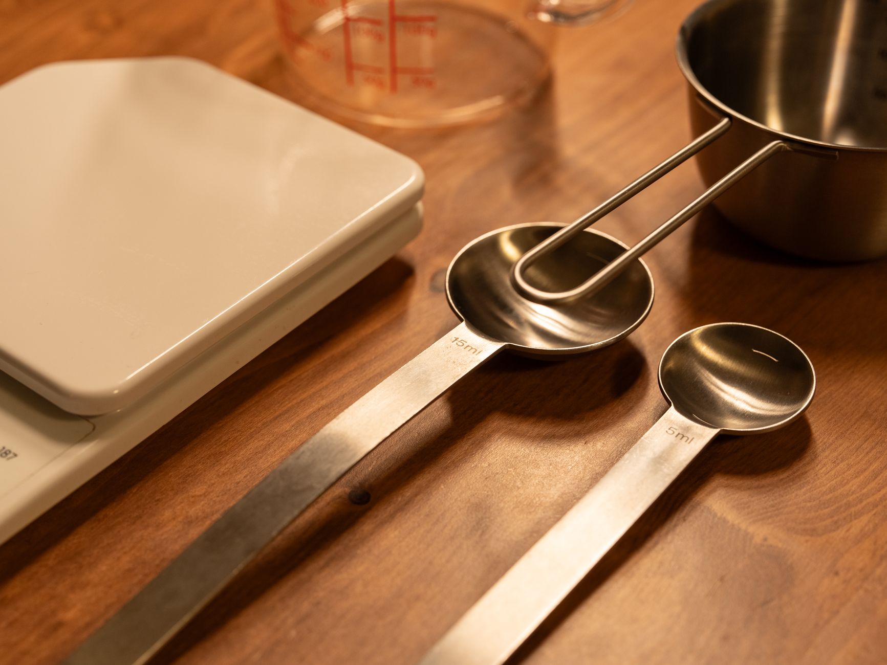 A close up of kitchen utensils including a scale, measuring cups, and spoons on a wooden counter, illustrating Where Should the Kitchen Stove Be Placed? A Feng Shui Guide