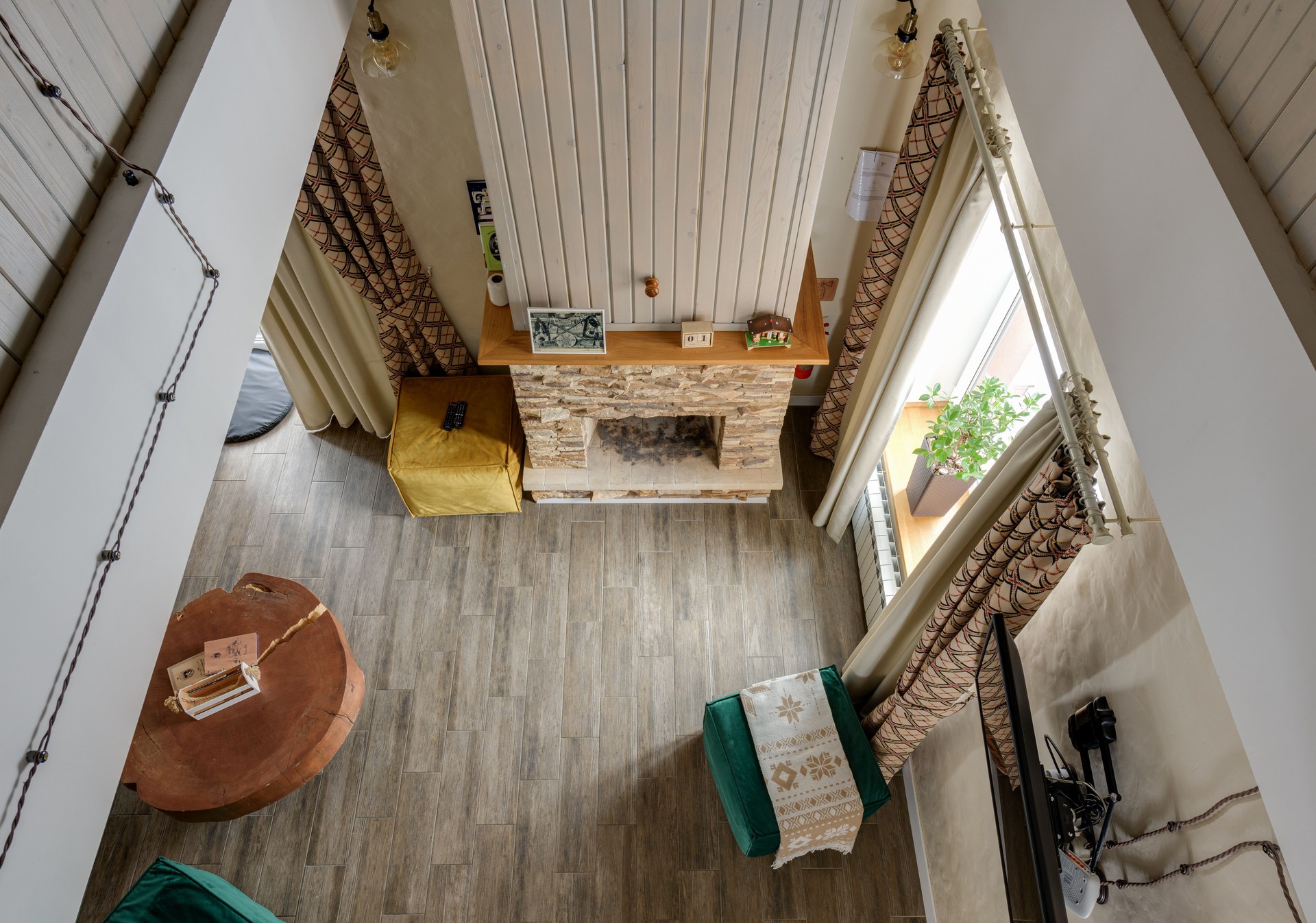 High-angle view of a stylish living room featuring a rustic fireplace and a wooden floor, showcasing modern interior design