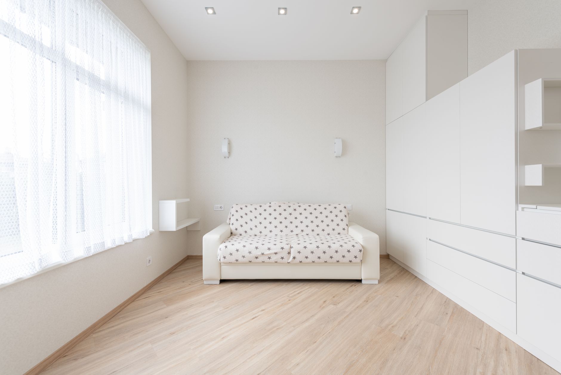 Interior of modern living room with sofa placed on parquet between window and white cupboards in light apartment with minimalist style, illustrating Why Do Feng Shui Rules Contradi