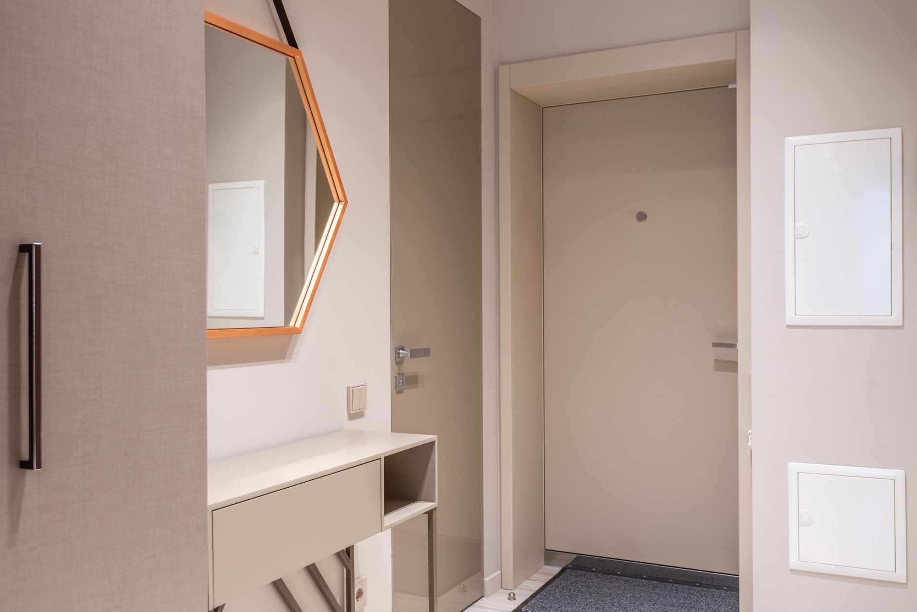 Contemporary corridor interior with beige doors and cabinet under hexagonal shaped mirror at home, illustrating Why Does Feng Shui Object to a Cluttered Entrance