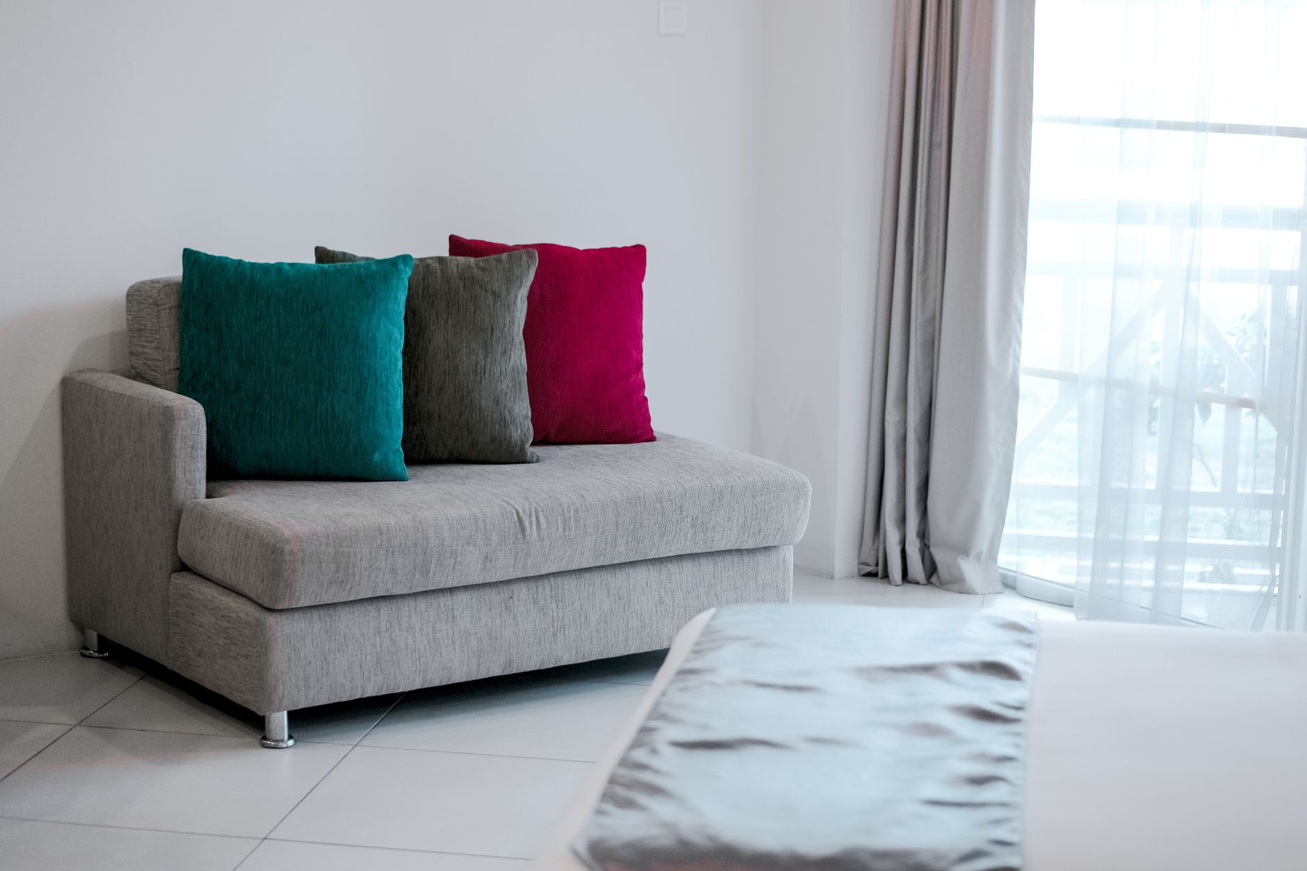 Simple modern interior featuring a grey sofa with vibrant colored cushions in a bright room